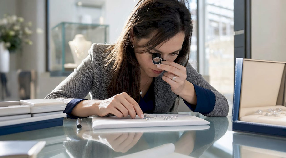 Woman examining loose gemstones with loupe